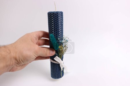 Aromatische handgemachte Wachskerze, verziert mit einem Blumenstrauß.