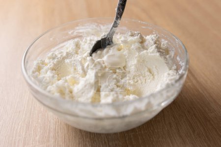Téléchargez les photos : La crème sure est ajoutée au fromage au lait aigre et mélangée. - en image libre de droit
