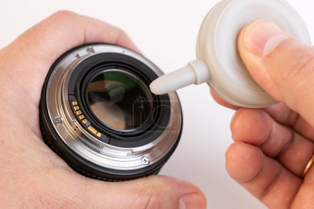Foto de La lente fotográfica es expulsada del polvo por una pera. Cuidado de la óptica fotográfica. - Imagen libre de derechos