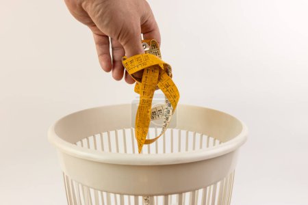 The measuring tape is thrown into the trash can. Disposal of household waste.