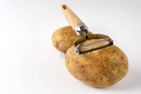 Photo for Raw potatoes and a knife for peeling on a white background. - Royalty Free Image