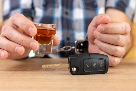 A glass of alcohol and car keys. The concept of driving under the influence of alcohol.
