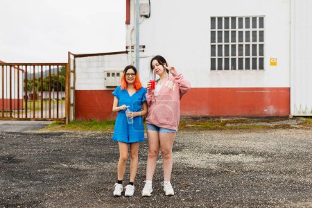 Téléchargez les photos : Deux jeunes filles, amies, sirotant du soda et s'étirant les jambes lors d'une escale en voiture - en image libre de droit