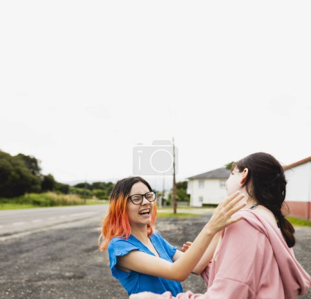 Téléchargez les photos : Deux jeunes filles en voyage, des amis, l'un d'eux avec les cheveux orange, bavardent et rient pendant qu'ils se reposent pendant un arrêt de voiture - en image libre de droit