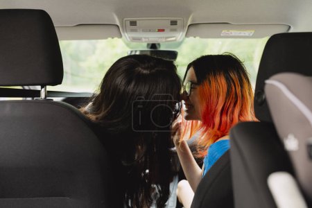 Téléchargez les photos : Deux jeunes lesbiennes s'embrassent dans la voiture lors d'un voyage en voiture - en image libre de droit