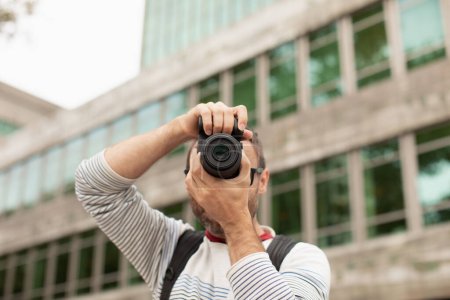 Foto de Un joven, un viajero, tomando fotos con una cámara digital, en la calle, en una ciudad de España. - Imagen libre de derechos