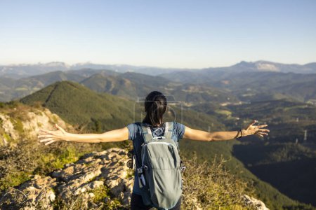 Foto de Una joven abre los brazos, maravillada con el paisaje natural de montaña del País Vasco - Imagen libre de derechos