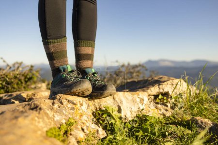 Foto de Detalle de las botas de un excursionista, desde la cima de una montaña, con el paisaje natural fuera de foco en el fondo - Imagen libre de derechos