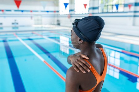 Photo for Black young woman touching her sore shoulder at the heated swimming pool - Royalty Free Image