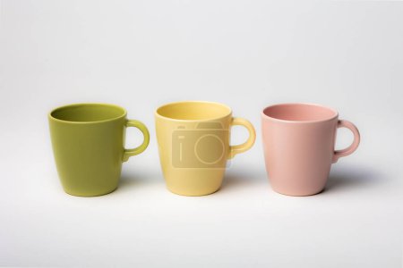Foto de Mockup de tres tazas de café de colores, o tazas, aisladas, de color verde, amarillo y rosa, perfecto para los diseños de capas o logotipos para merchandising - Imagen libre de derechos