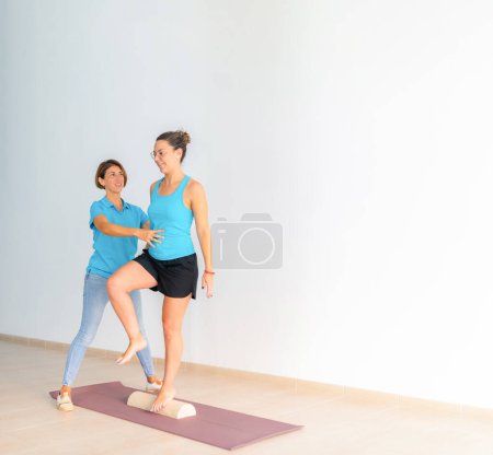 Foto de Un fisioterapeuta ayuda a un paciente, durante una sesión de ejercicios terapéuticos de Pilates - Imagen libre de derechos