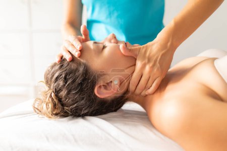 Foto de Una fisioterapeuta realiza un masaje descontrayente y relajante en el cuello de su paciente para aliviarla del dolor y la tensión. - Imagen libre de derechos