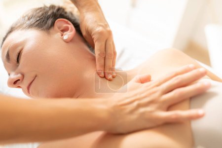 Foto de Una paciente, completamente relajada, disfruta recibir un masaje de su fisioterapeuta en la zona del cuello - Imagen libre de derechos
