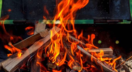 Schöne orangerote Flamme aus brennendem Brennholz auf dem Grill. Zubereitung eines Grills zum Kochen in der Natur. Konzepturlaub in der Natur