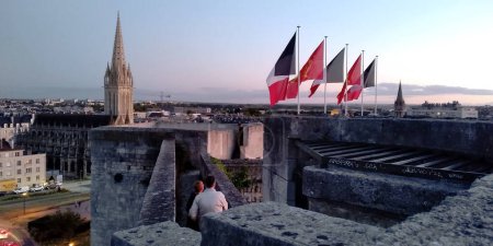 Foto de CAEN, FRANCIA - 1 DE SEPTIEMBRE DE 2019: Esta es una vista de la ciudad y las banderas por encima de las puertas principales de las paredes del castillo de Caen por la noche. - Imagen libre de derechos