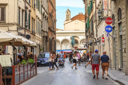 Foto de FLORENCIA, ITALIA - 12 DE SEPTIEMBRE DE 2018: Esta es una animada calle medieval del Servi cerca de Piazza Santissima Annunziata con un monumento al duque Fernando I de los Médici. - Imagen libre de derechos