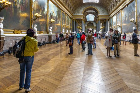 Téléchargez les photos : VERSAILLES, PARIS - 12 MAI 2013 : Des visiteurs non identifiés examinent des peintures dans la galerie des batailles du château de Versailles. - en image libre de droit