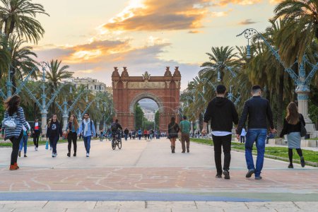 Téléchargez les photos : BARCELONE, ESPAGNE - LE 12 MAI 2017 : Des personnes non identifiées se promènent le long du boulevard Lluis Companys à travers l'arche de triomphe au coucher du soleil - en image libre de droit