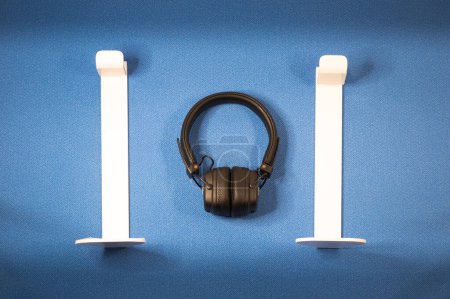 Téléchargez les photos : Écouteurs sur un fond bleu, avec des supports d'inserts blancs pour eux - en image libre de droit