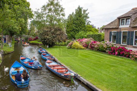 Téléchargez les photos : GIETHOORN, PAYS-BAS - 01 AOÛT 2017 : Visiteurs inconnus lors du voyage en bateau dans un canal de Giethoorn. Les belles maisons et la ville de jardinage est connu comme "Venise du Nord". - en image libre de droit
