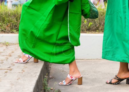Foto de Piernas de estudiantes universitarios graduados con su traje de graduación verde y marchando hacia la sala de recepción de la escuela para su ceremonia de desmayo en Nigeria - Imagen libre de derechos