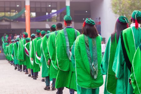 Téléchargez les photos : Alignement des étudiants diplômés universitaires portant leur tenue de fin d'études vertes et marchant vers la salle de réception de l'école pour leur cérémonie de remise des diplômes au Nigeria - en image libre de droit