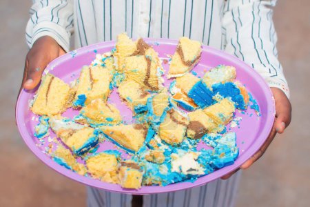 Téléchargez les photos : Une personne africaine ou steward de fête portant un plateau rempli de petits morceaux de délicieux gâteaux à la recherche lors d'un événement en plein air au Nigeria - en image libre de droit