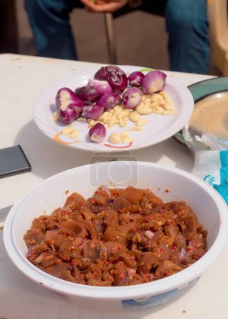Foto de Surtido de piel de vaca cocida, cortada en cubitos y frita u ocultar, colocado dentro de un plato blanco en una mesa con otros ingredientes alimentarios en un restaurante de cocina en Nigeria - Imagen libre de derechos