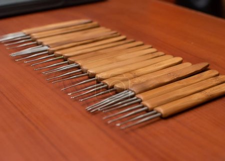 Foto de Múltiples herramientas de ganchillo pelo de madera colocadas en una mesa de madera contrachapada, dispuestos en una línea recta para las ventas dentro de una tienda de negocios de salón y moda en Nigeria - Imagen libre de derechos