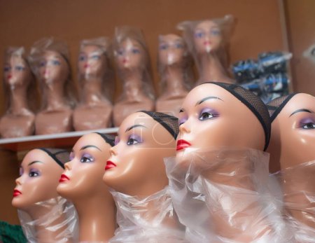 Téléchargez les photos : Gros plan de mannequin multiple avec filet à cheveux, présenté côte à côte pour les ventes dans un salon et boutique de mode au Nigeria - en image libre de droit