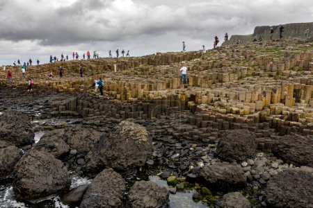 Photo for Antrim, Northern Ireland - August 18, 2013: Group of tourists exploring the Giant's Causeway in the Summer of 2013. - Royalty Free Image