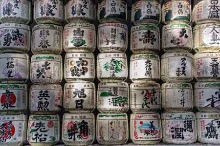 Téléchargez les photos : Traditional Sake barrels at the entrance to Meiji shrine in Tokyo.. The writings in Japanese inform of the content of barrels and religious verses - en image libre de droit