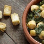 Chickpea and spinach stew on rustic wooden background. Spanish cuisine.