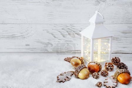 Téléchargez les photos : Décoration de Noël. Lanterne sur neige avec glands et feuilles de chêne - en image libre de droit
