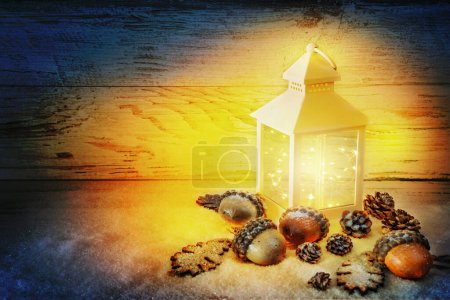 Photo for Xmas time. Christmas Lantern On Snow with acorns and oak leaves In Evening Scene. - Royalty Free Image