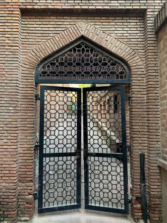 Decorative metal arched closed or locked gate leading to the Shahi Hammam (Turkish Bathrooms) in the Delhi Gate, Walled City Lahore, Pakistan. (Built during 635 C.E.)