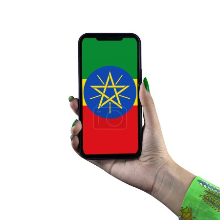 Téléchargez les photos : L'affichage du drapeau éthiopien dans un smartphone tenu par une jeune femme asiatique ou la main d'une femme. Patriotisme avec affichage moderne de technologie de téléphone portable. Isolé sur fond blanc. - en image libre de droit