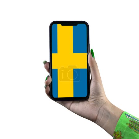Téléchargez les photos : Le drapeau suédois est affiché sur un smartphone tenu par une jeune femme asiatique ou la main d'une femme. Isolé sur fond blanc. Patriotisme avec affichage moderne de technologie de téléphone portable. - en image libre de droit