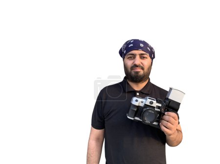 Téléchargez les photos : Un jeune homme avec un bandana arabe pose avec un vieil appareil reflex. Isolé sur fond blanc. - en image libre de droit