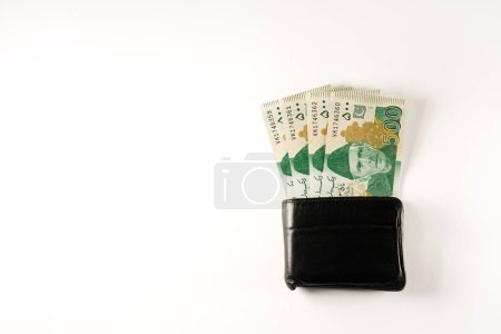 Five hundred rupee bank notes aligned with a black leather wallet. Pakistan State Bank official currency notes 2024 isolated on a white background.