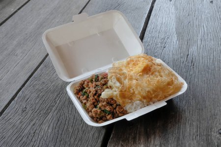 Téléchargez les photos : Une boîte de riz garnie de porc frit, basilic et frit par exemple - en image libre de droit