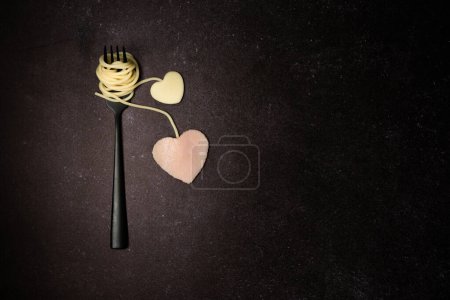 Foto de Creative food love concept made with spaghetti, cheese and ham on dark black background. Heart-shaped food and pasta layout. - Imagen libre de derechos