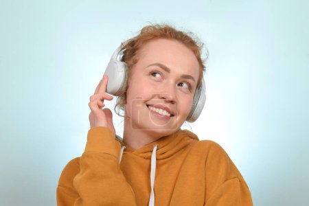 Cute redhead curly woman enjoying music in headphones