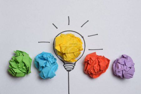 Boules de papier froissées colorées et ampoule comme concept créatif