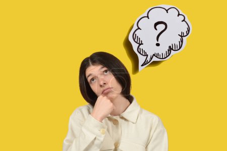 thoughtful young woman on yellow background, question mark-stock-photo