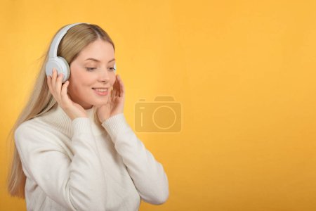 Cute young blonde woman enjoying music in headphones