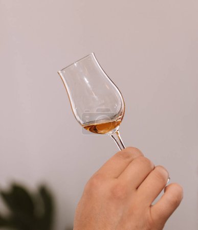 Verre de cognac tenu en main lors d'une présentation de boissons sélectionnées avec des amis et des amateurs de boissons fortes.