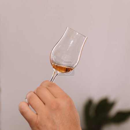 Photo for Glass of cognac held in hand at a presentation of selected drinks with friends and lovers of strong drinks. - Royalty Free Image
