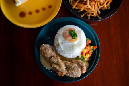 Chicken cordon bleu mit Reis und Ei in einem Teller serviert.