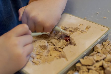 Foto de The child is busy excavating minerals hidden in a special plaster - Imagen libre de derechos